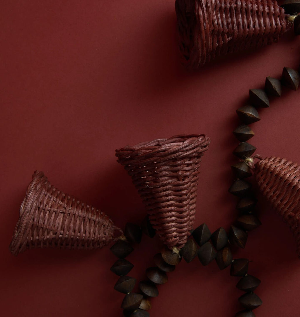 A wooden bead and wicker bell garland set against a red background