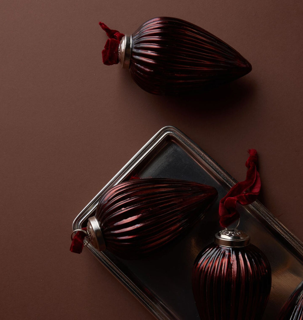Ribbed brown ornaments arranged on a pewter tray against a light brown background 
