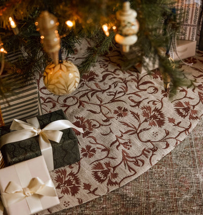 A christmas scene of an embroidered tree skirt under a styled tree with wrapped gifts 