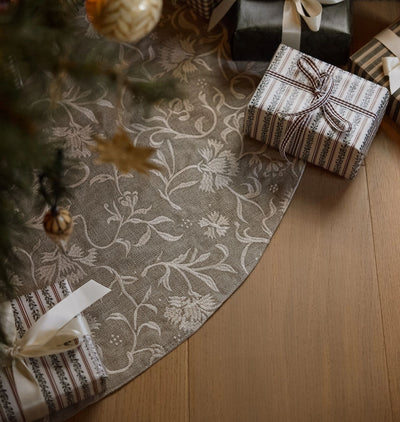 A christmas scene of an embroidered tree skirt under a styled tree with wrapped gifts 