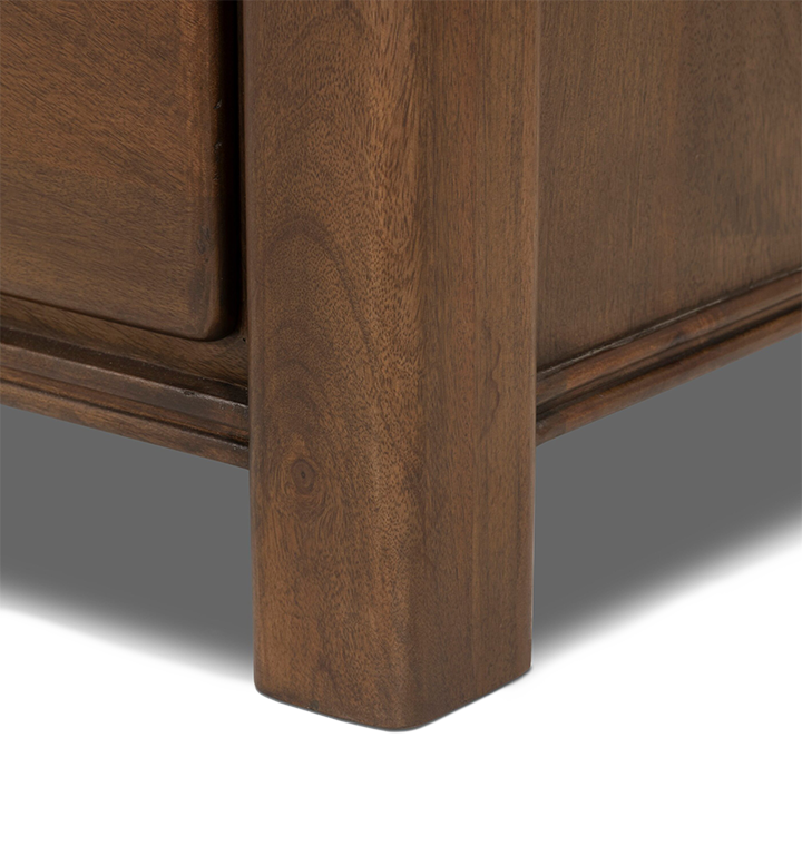 A close up detailed view of a wooden nightstand leg against a plain light gray background.