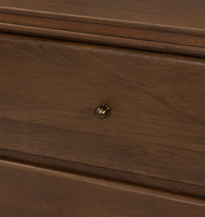 A close up view of a two-drawer wooden nightstand with small round brass knobs, shown against a plain light gray background.