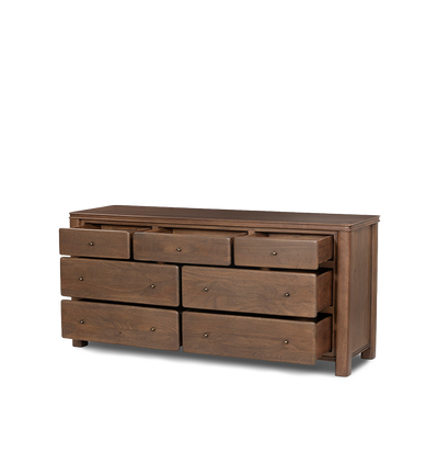 An angled open drawer view of a five-drawer wooden chest of drawers with small round brass knobs, shown against a plain light gray background.