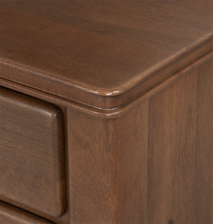 A close up view of a wooden dresser with small round brass knobs, shown against a plain light gray background.