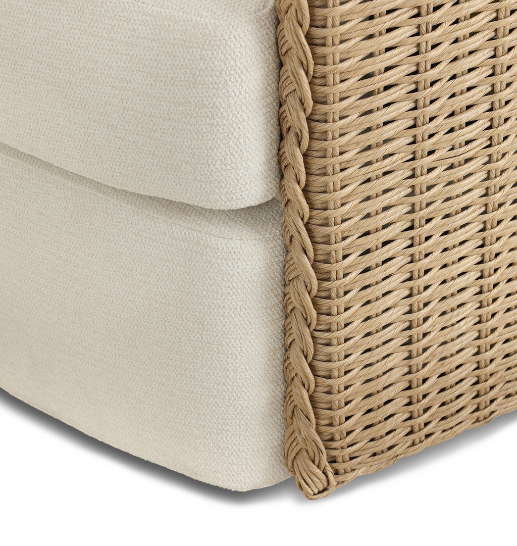 A curved outdoor swivel chair with a woven braided wicker back and sides and plush off white tufted seating