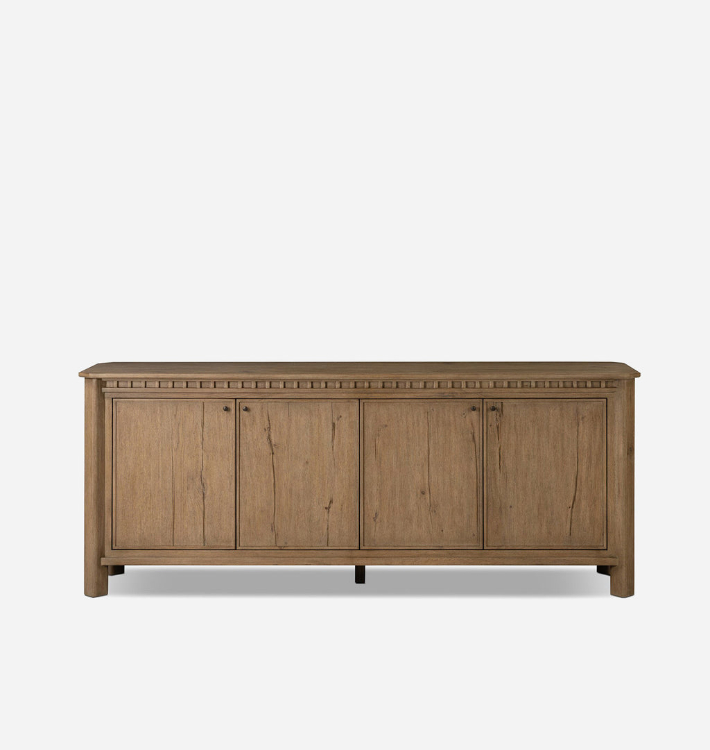 A rustic wood sideboard cabinet with four doors, small round knobs, and a decorative border along the top, shown against a plain light gray background.
