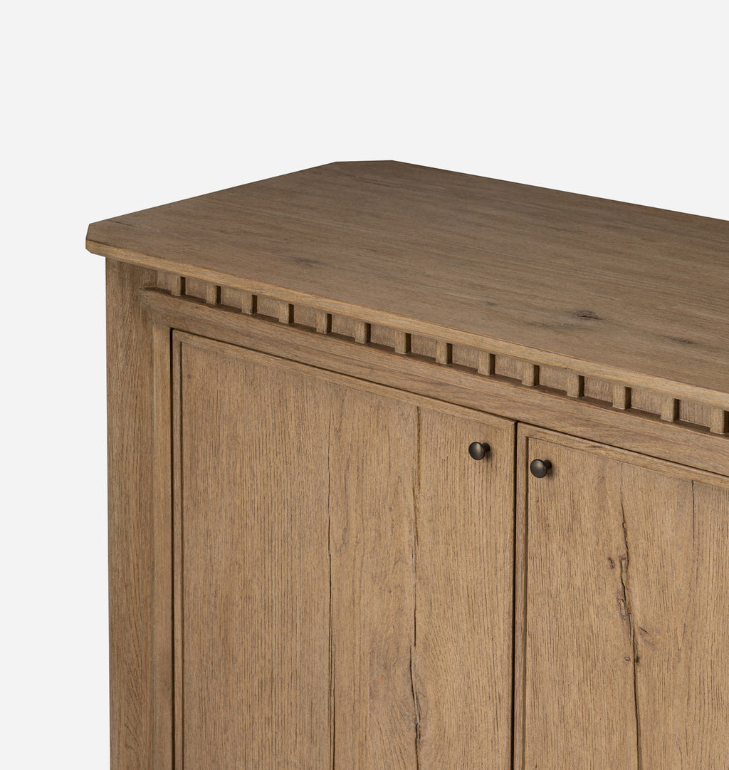 Close-up of a wooden cabinet with two doors, dark round knobs, and a decorative raised border along the top front, shown against a plain light background.