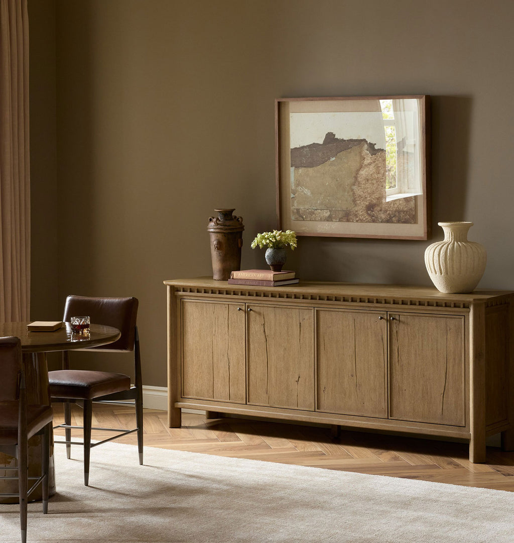 A rustic wood sideboard cabinet with four doors, small round knobs, and a decorative border along the top.