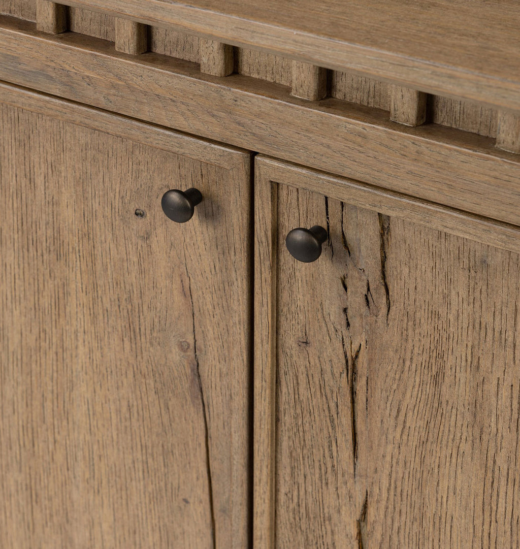 Close-up of a rustic wooden cabinet with two doors and round black metal knobs, showing detailed wood grain texture.