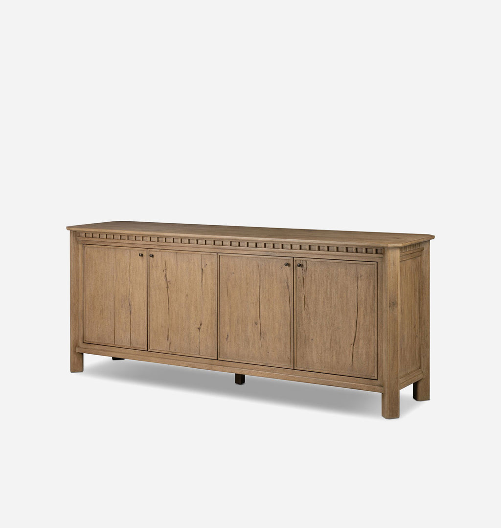 A long wooden sideboard cabinet with four paneled doors, small decorative molding along the top, and dark metal handles, shown on a plain light gray background.