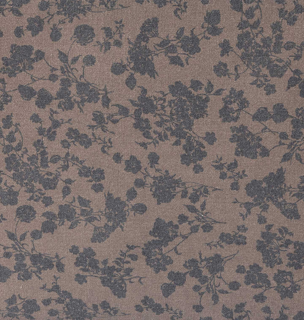 A close-up of a textured fabric or wallpaper pattern featuring a dark slate blue floral and leafy design on a warm taupe-brown background.