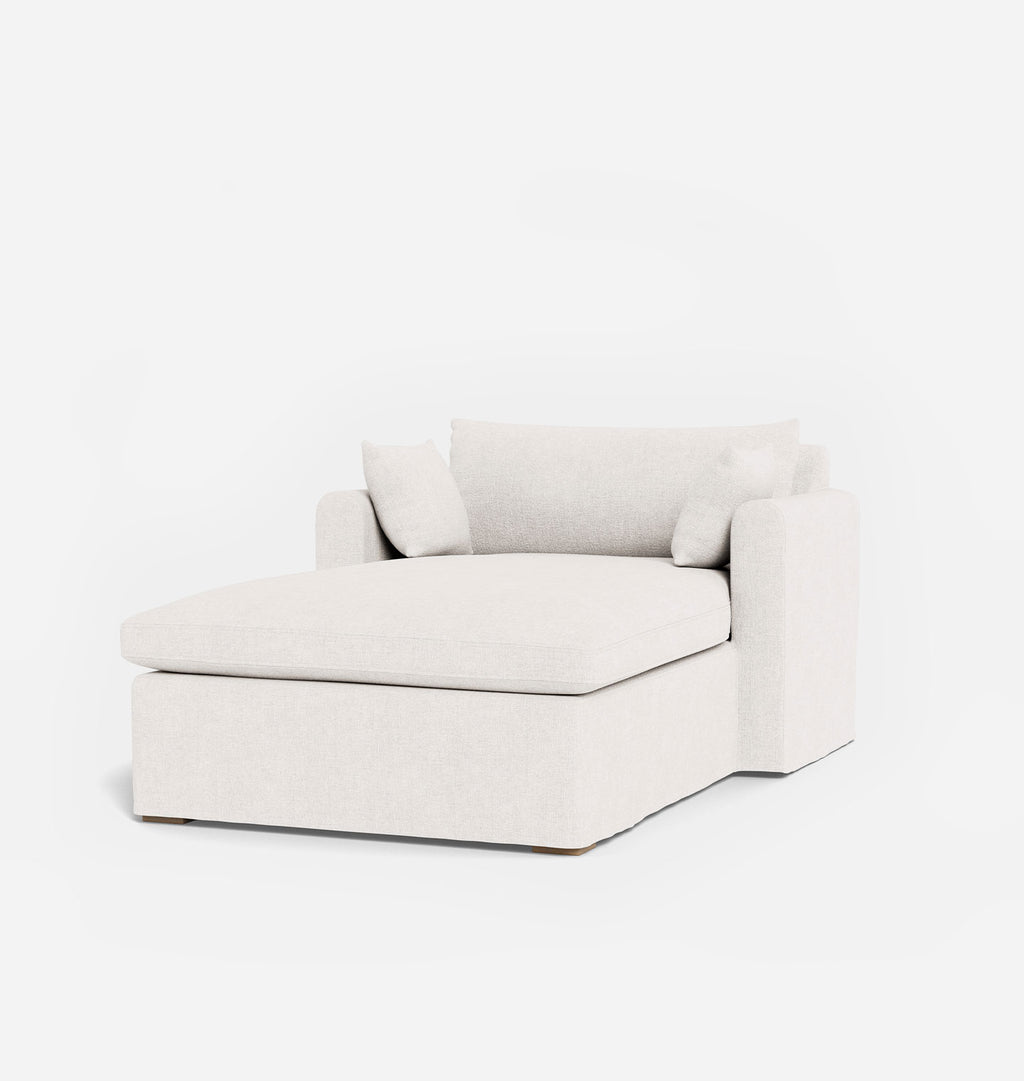 A modern off-white upholstered chaise lounge chair with two matching throw pillows, shown on a seamless white background.