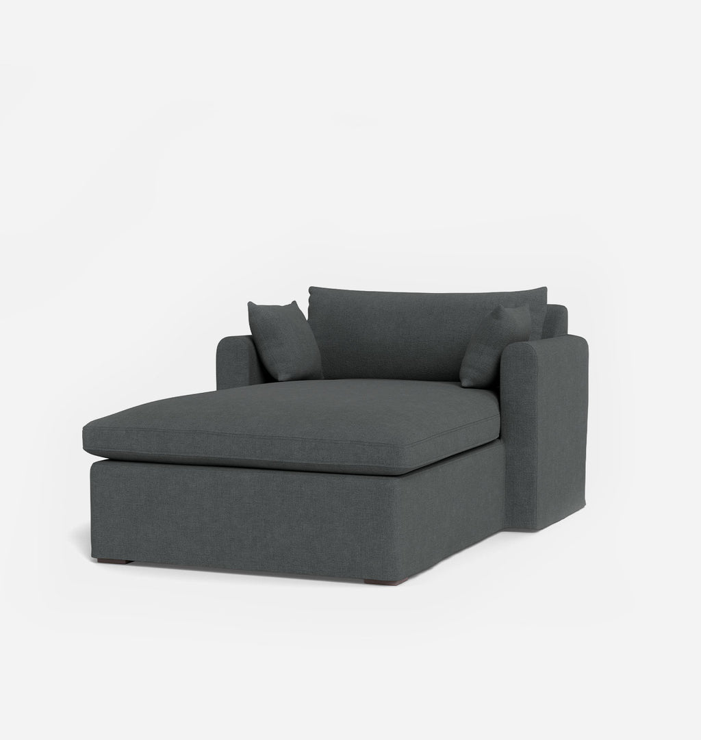 A modern dark blue grey fabric chaise lounge chair with two matching throw pillows, shown on a clean white background.