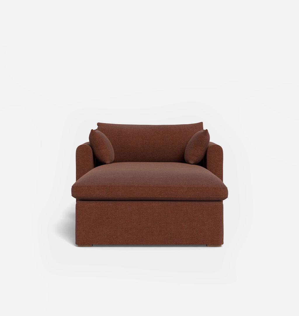 A brown upholstered chaise lounge chair with two small back cushions, shown against a plain light gray studio background.