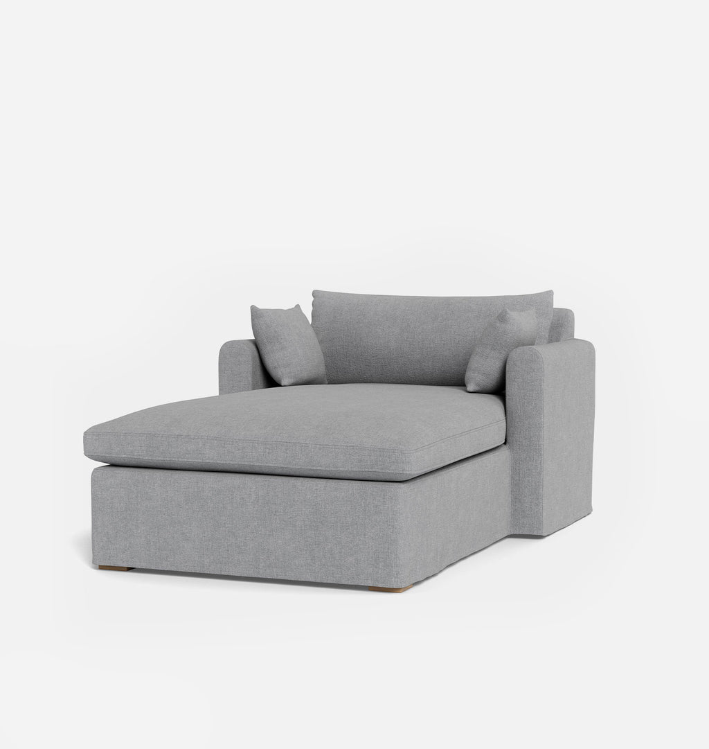 A modern gray fabric chaise lounge chair with two matching throw pillows, shown on a clean white background.