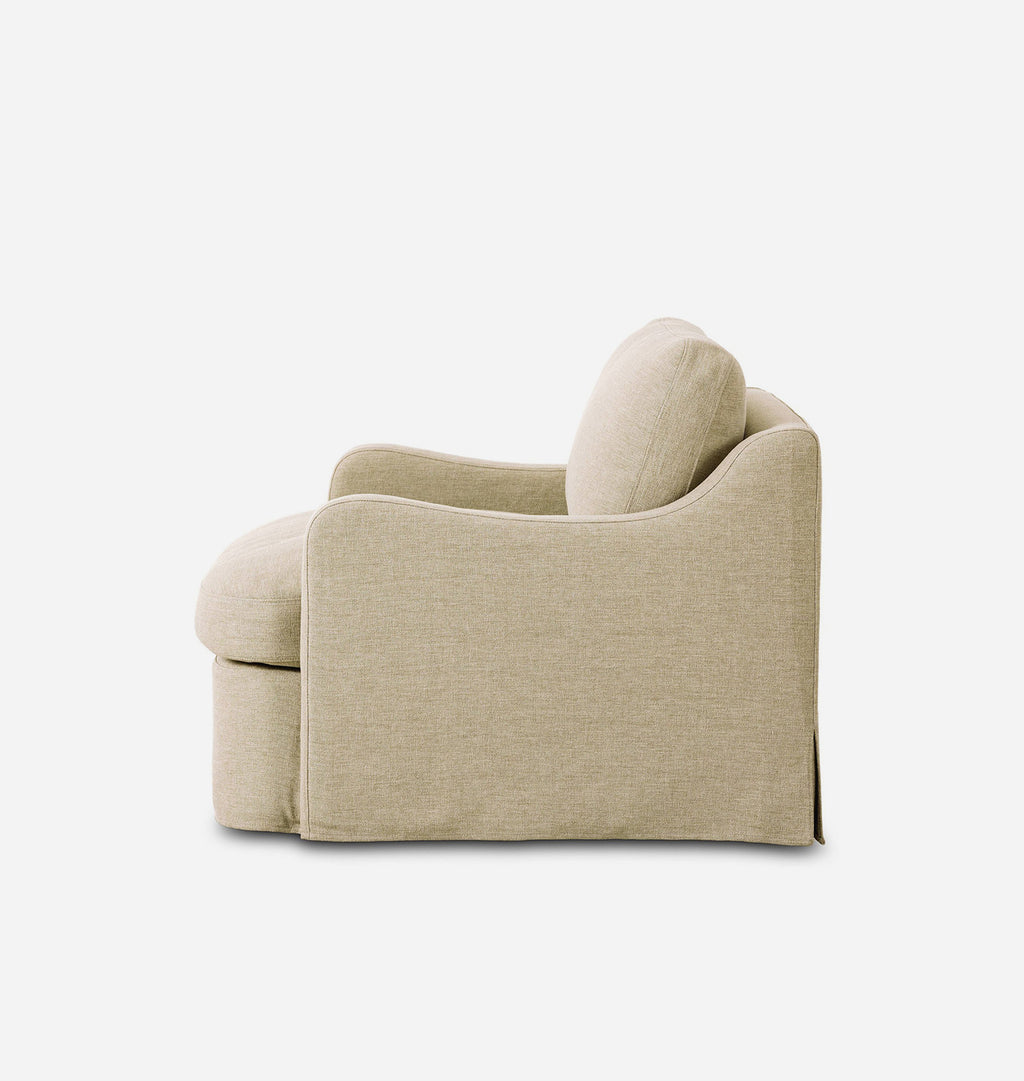 A modern slipcovered armchair in a light beige textured fabric, shown from a side-rear angle against a plain white background.