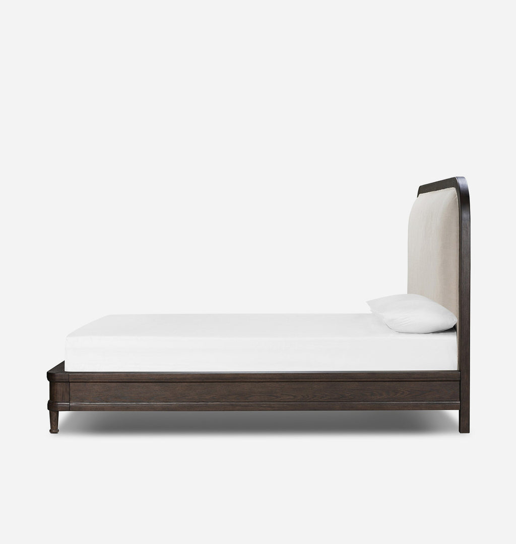A modern single bed frame with a dark brown wood finish and a tall, curved upholstered headboard in a light beige fabric, shown with a white mattress and pillow against a plain white background.