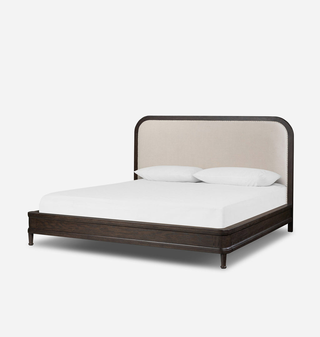 A modern platform bed with a dark brown wood frame and a tall, curved upholstered headboard in a light beige fabric, shown with a white mattress and two white pillows on a light gray background.