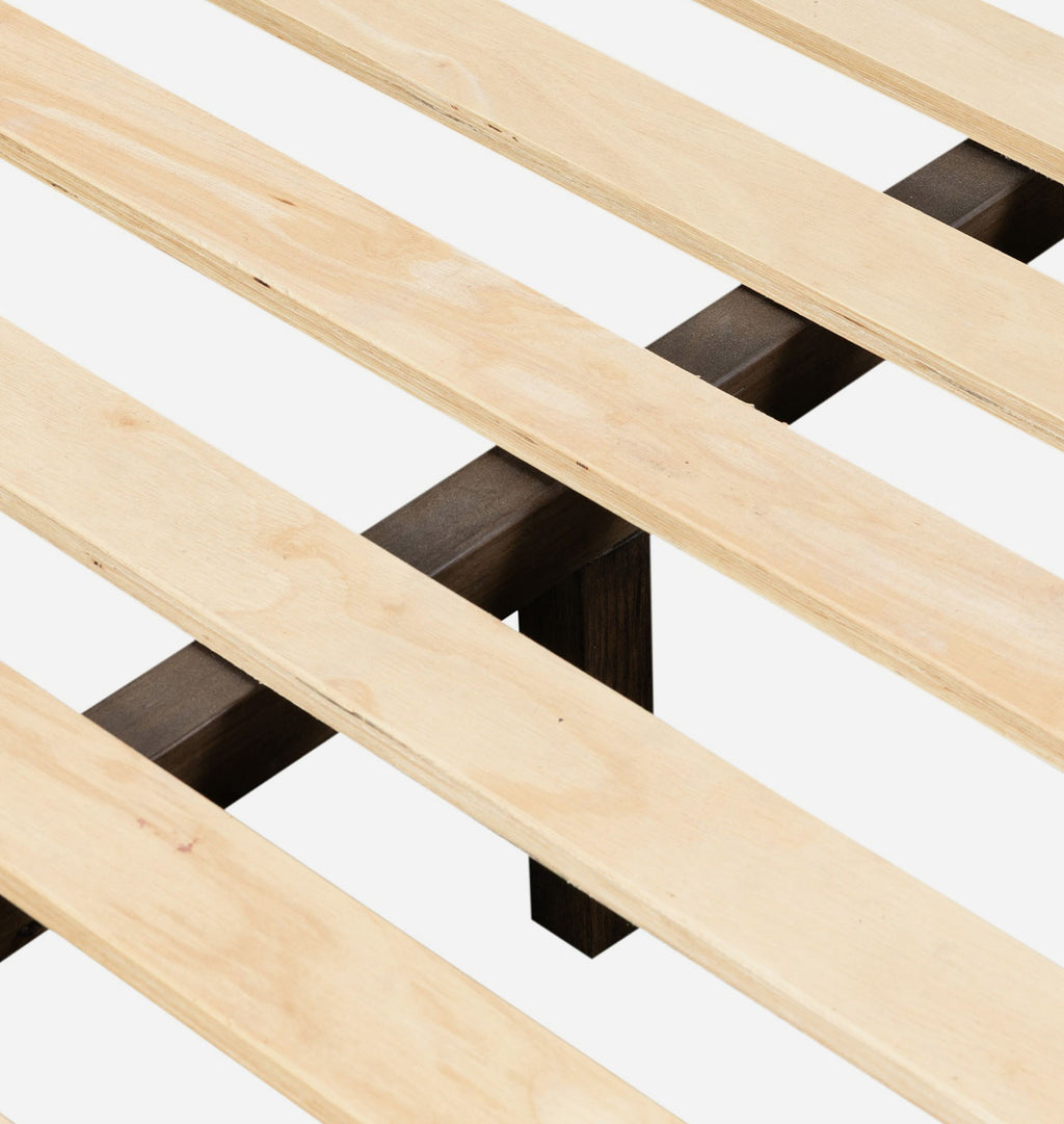 Close-up of a wooden slatted bed frame with light natural wood planks and dark brown support brackets on a white background.