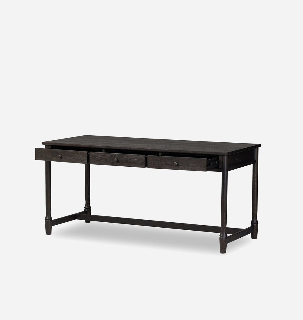 A dark brown wooden writing desk with three drawers on the front, supported by four turned legs and a lower stretcher bar, shown against a light gray background.
