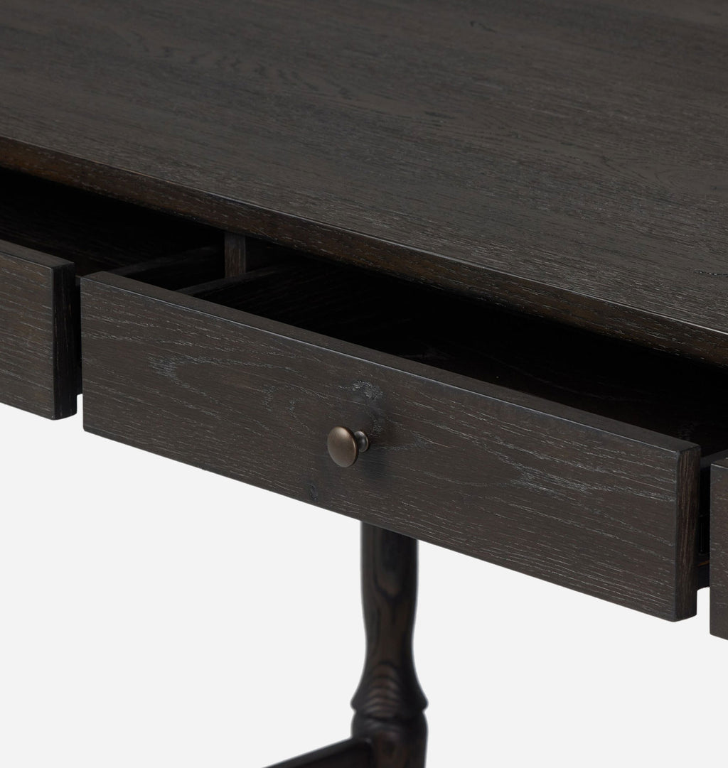 Close-up of a dark wood writing desk with an open drawer showing a round metal pull knob, on a light gray background.