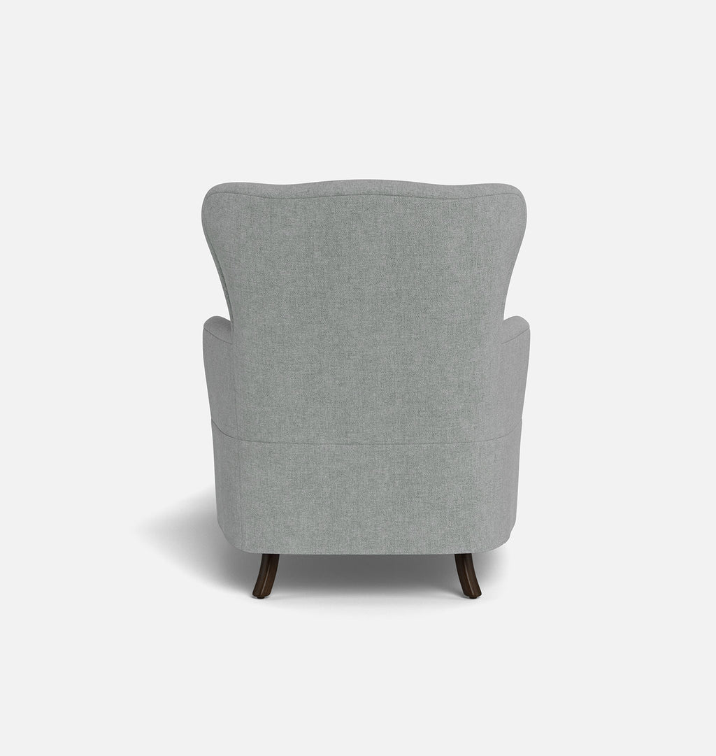 A light gray upholstered armchair shown from the back, featuring a wingback-style backrest and dark wooden legs, set against a plain white background.