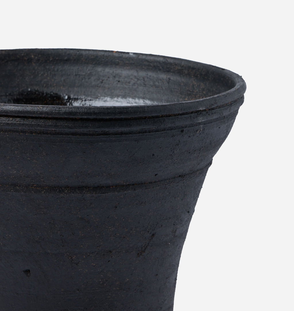 Close-up of a dark charcoal gray ceramic planter pot showing the textured exterior and flared rim against a plain white background.