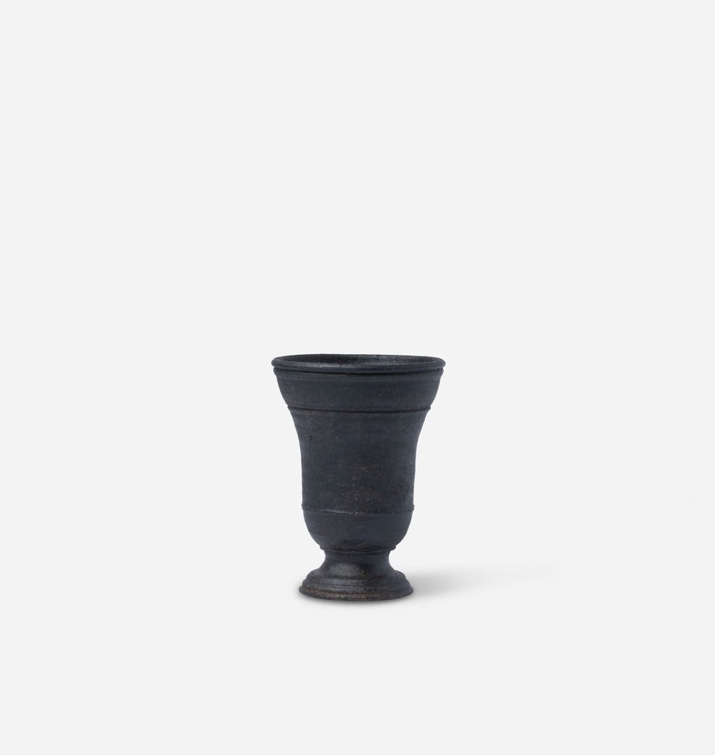 A dark charcoal gray ceramic small vase with a flared rim and pedestal base, centered on a light gray background.