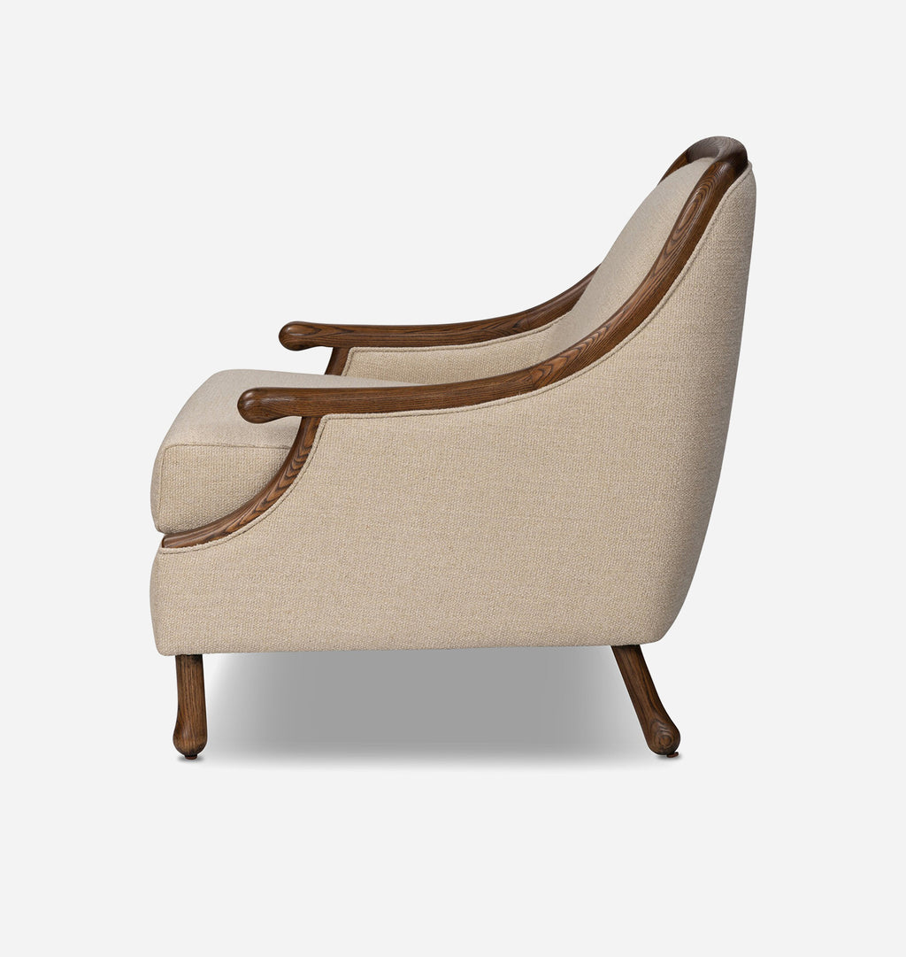 A classoc accent chair with beige textured fabric upholstery and dark brown wooden arms, backrest trim, and legs, shown from a side profile view on a light gray background.