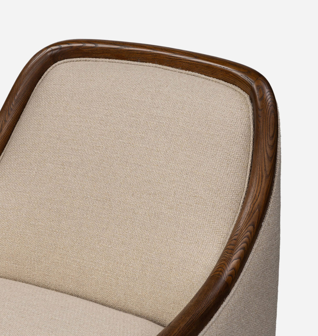 Close-up of an upholstered armchair corner showing a beige textured fabric seat and back with a curved dark brown wooden frame on a light gray background.