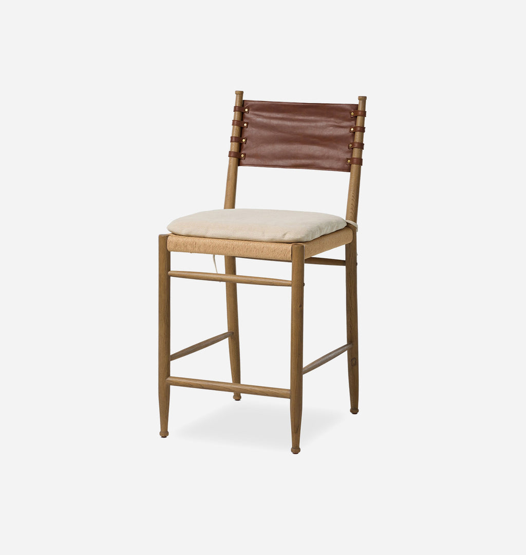 A wooden bar stool with a brown leather backrest, a beige upholstered seat cushion, and a light wood frame, shown against a plain light gray background.