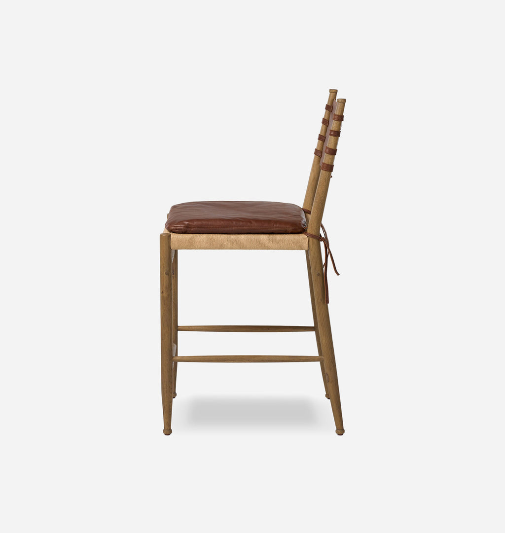 A wooden ladder-back chair with a brown leather seat cushion and tie straps, shown from a side-rear angle against a light gray background.