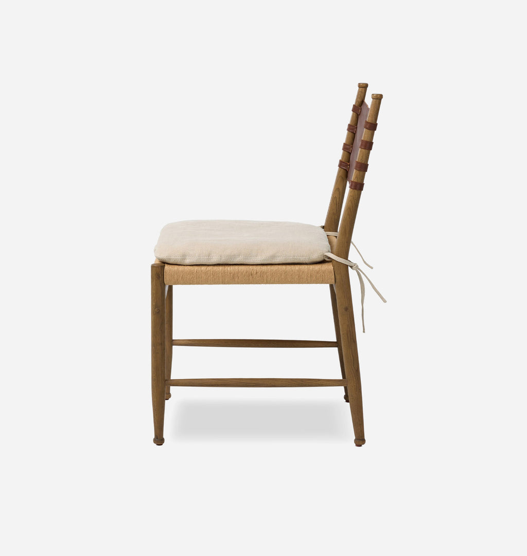 A wooden ladder-back chair with a woven cane seat and a cream-colored cushion, shown from the side against a plain white background.