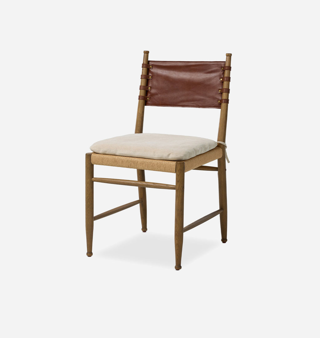 A mid-century modern wooden dining chair with a light beige upholstered seat cushion, a brown leather sling backrest, and a natural wood frame, shown against a plain light gray background.