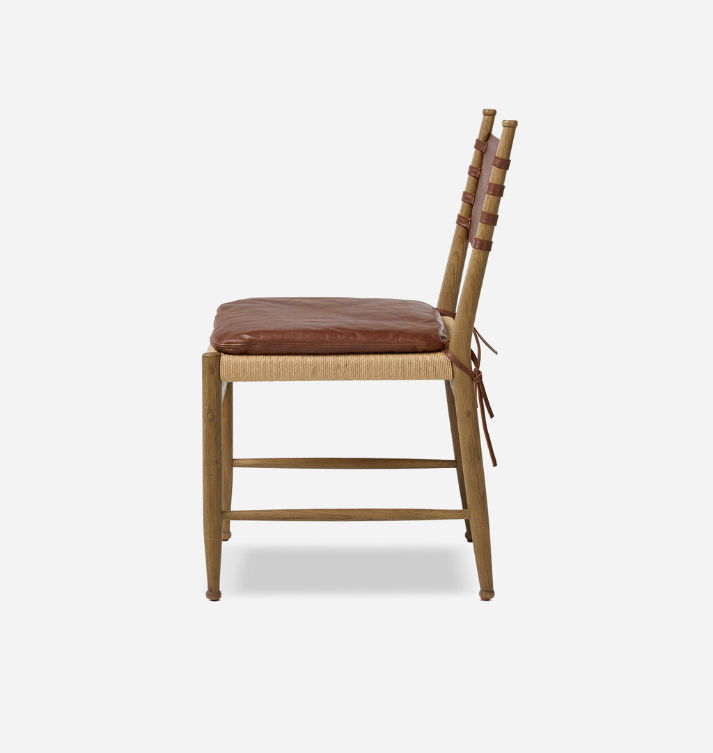 A wooden chair with a brown leather seat cushion and matching tie details on the backrest, shown from a side angle against a light gray background.