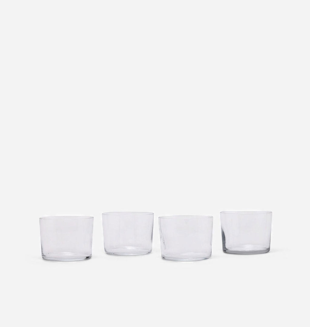 Four clear glass tumblers arranged in a row against a plain white background.