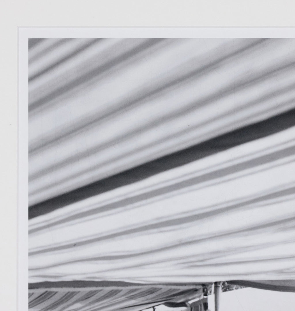A close-up of a striped fabric canopy or tent material in light gray, white, and black tones, with diagonal folds and a dark stripe running across the surface.