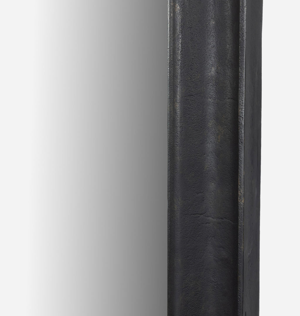 A close up detail shot of an oversized black aluminium floor mirror with curved corners and a thick frame set against a white background
