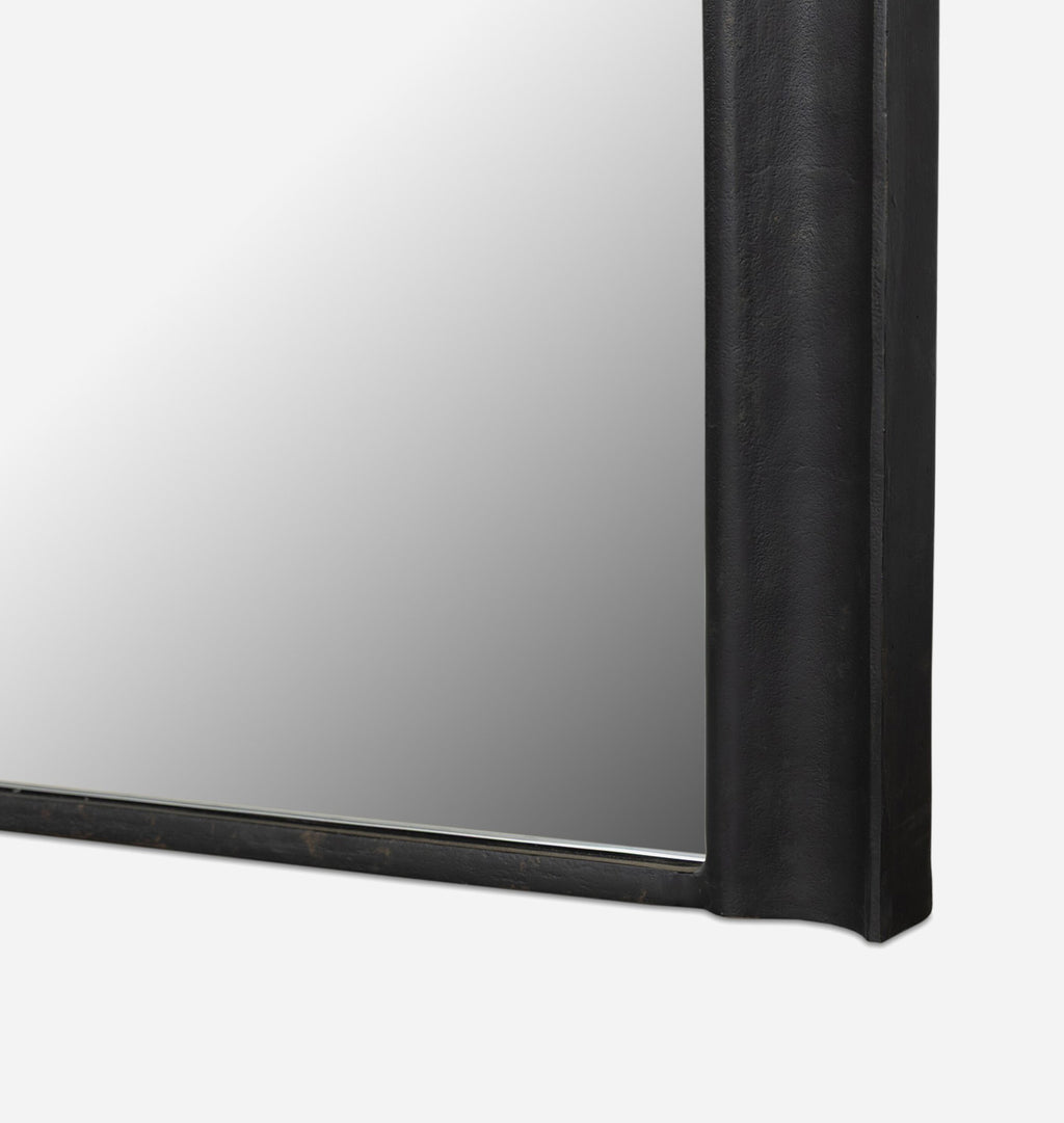 A close up detail shot of an oversized black aluminium floor mirror with curved corners and a thick frame set against a white background