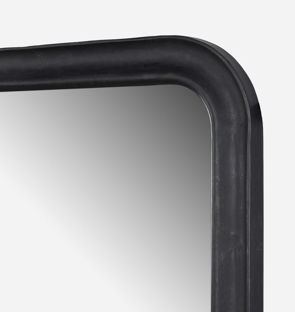 A close up corner shot of an oversized black aluminium floor mirror with curved corners and a thick frame set against a white background