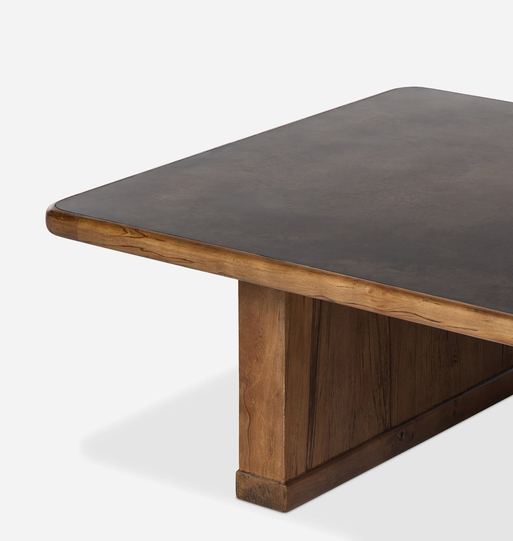 Close-up of a wooden table corner showing a dark brown top with a natural wood edge and a matching wood pedestal base on a light gray background.