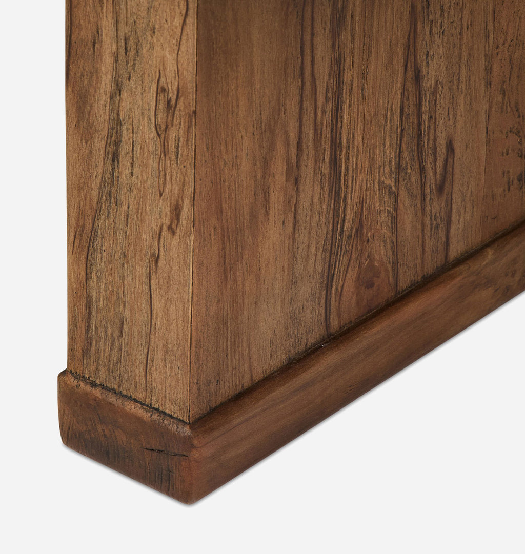 Close-up detail of a wooden coffee table base showing the grain, finish, and baseboard on a light gray background.