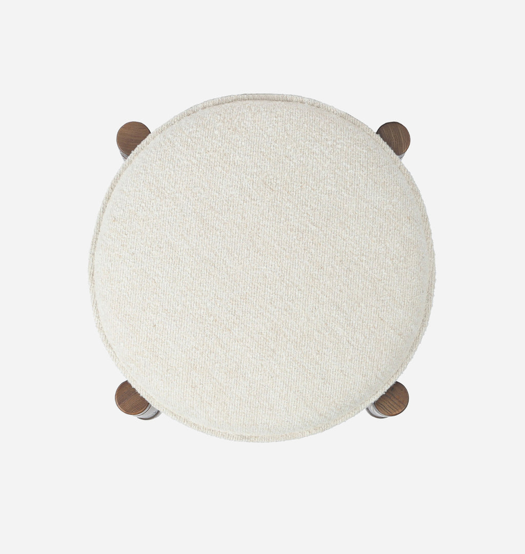 A top down view of a modern bar stool with dark wood legs and an off white upholsered cushion