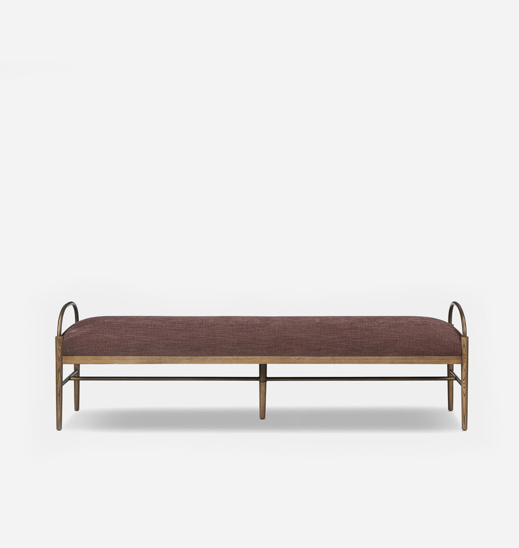 A modern bench with a rectangular cushion upholstered in a textured mauve-brown fabric, supported by a natural wood frame with curved metal side handles and legs, shown against a light gray background.