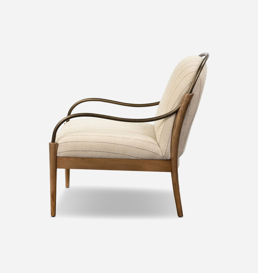 A modern accent chair with a light beige ribbed fabric upholstery, a medium brown wooden frame, and curved dark metal armrests, shown from a side profile on a light gray background.
