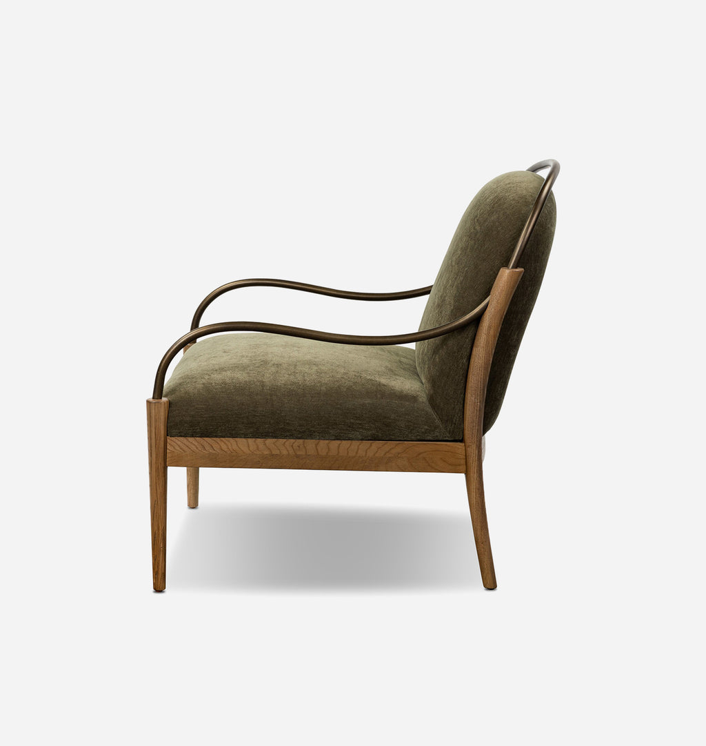 A mid-century modern accent chair featuring olive green velvet upholstery, a curved dark metal frame, and a light oak wood base, shown from a side profile on a light gray background.