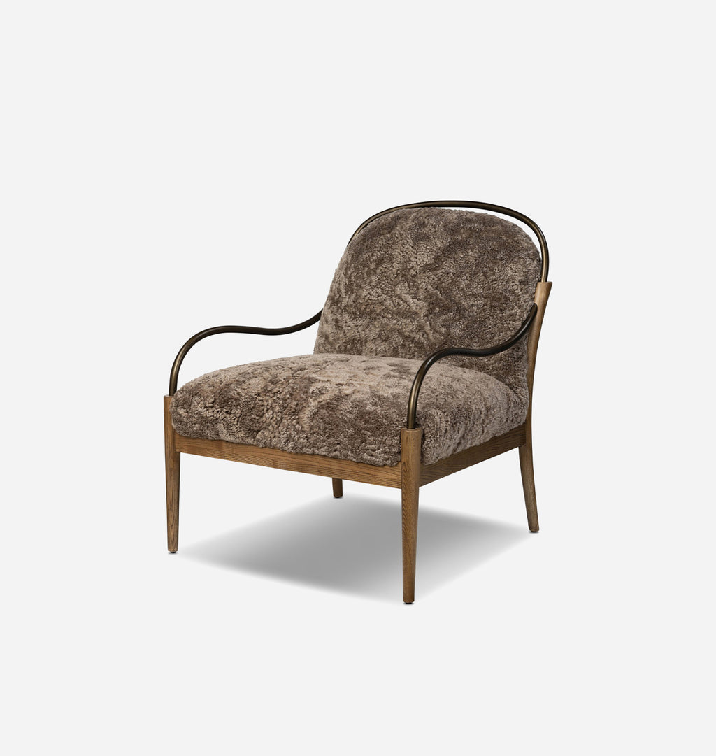 A modern accent chair with textured brown shearling upholstery, a light wood frame, and curved black metal armrests, shown against a plain light gray background.