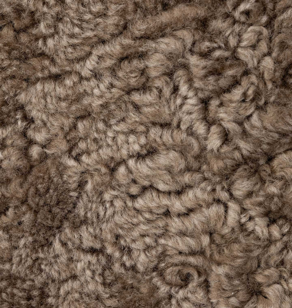 A close-up texture shot of a shaggy, curly fur fabric in a mottled taupe-brown color.