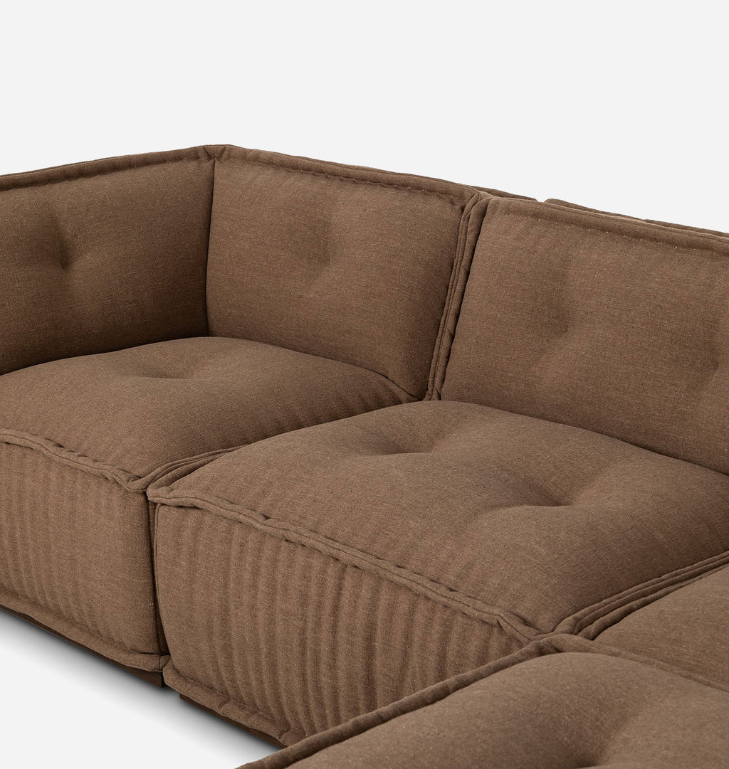 Close-up of a brown tufted modular sofa cushion with ribbed fabric, shown against a plain light background.