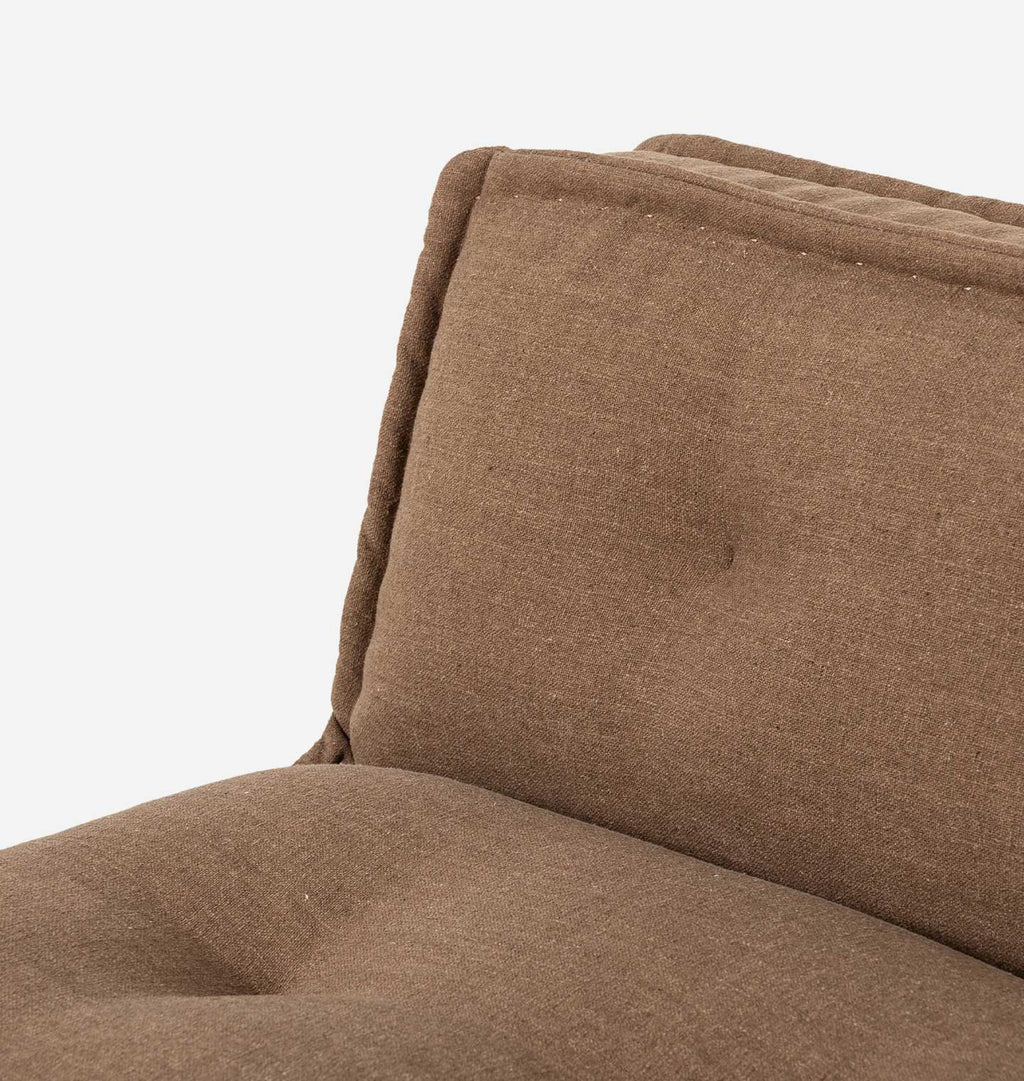 Close-up of a brown upholstered chair or sofa cushion showing the fabric texture and tufted detail against a plain white background.